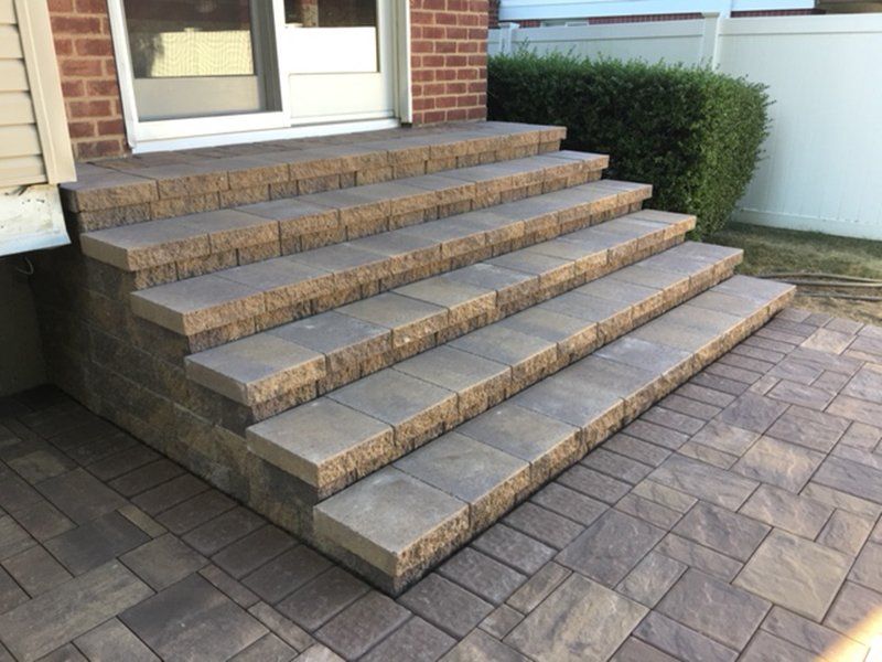 light grey steps with hand rail, leading to the front door of a house