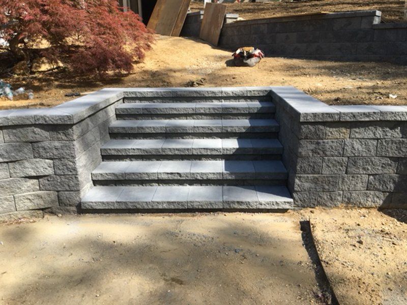 grey steps with a stone fence wall coming out on the left and right side of steps