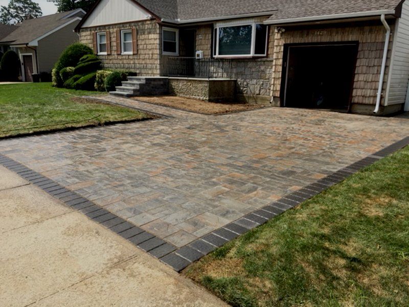 front of house with 3 garage doors showing the grey brick driveway