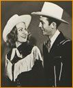 A man and a woman in cowboy hats are looking at each other.