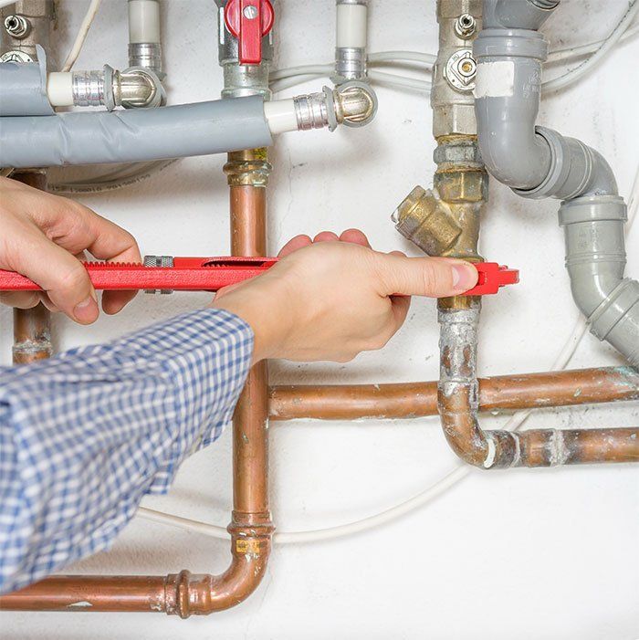 a person is fixing a pipe with a wrench .