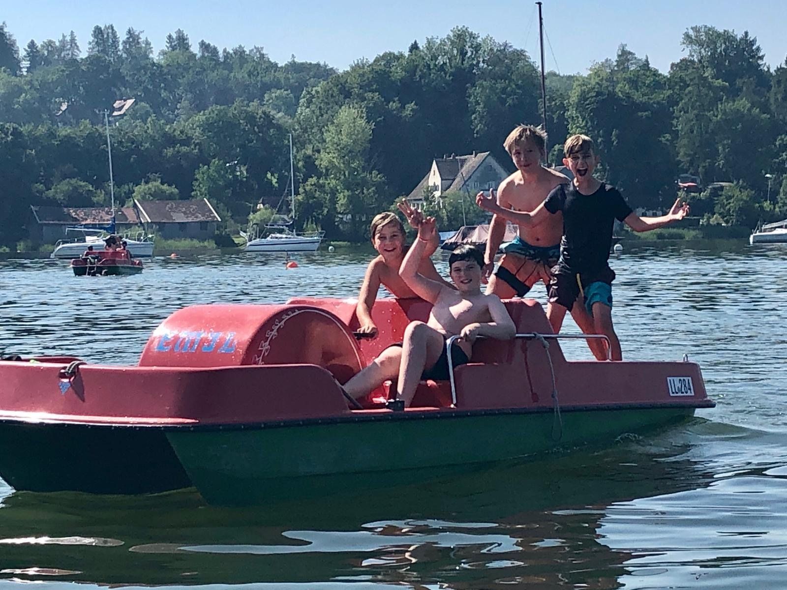 Eine Gruppe von Menschen fährt mit einem Tretboot auf einem See.