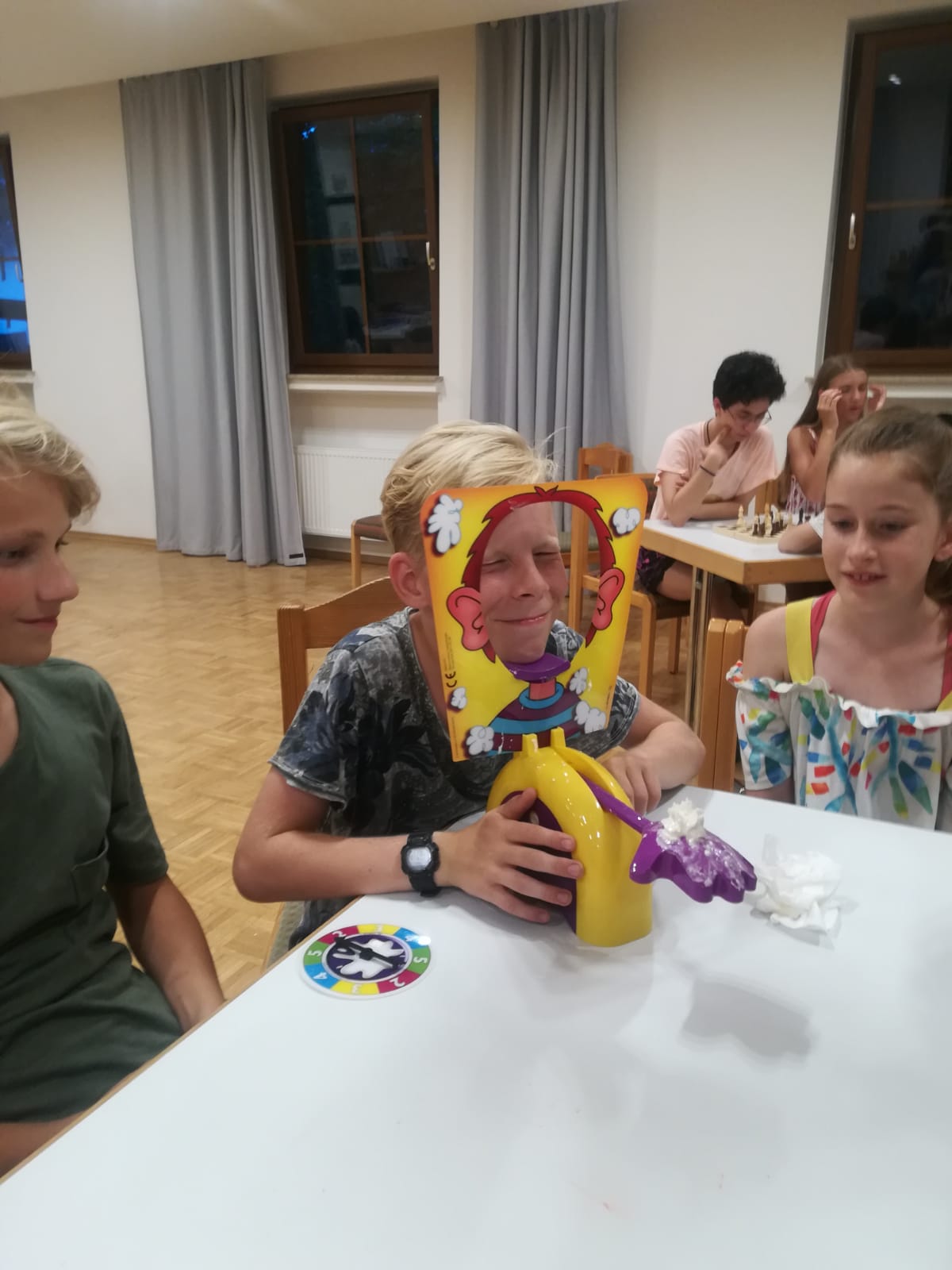 Ein Junge sitzt an einem Tisch und spielt eine Torte im Gesicht.