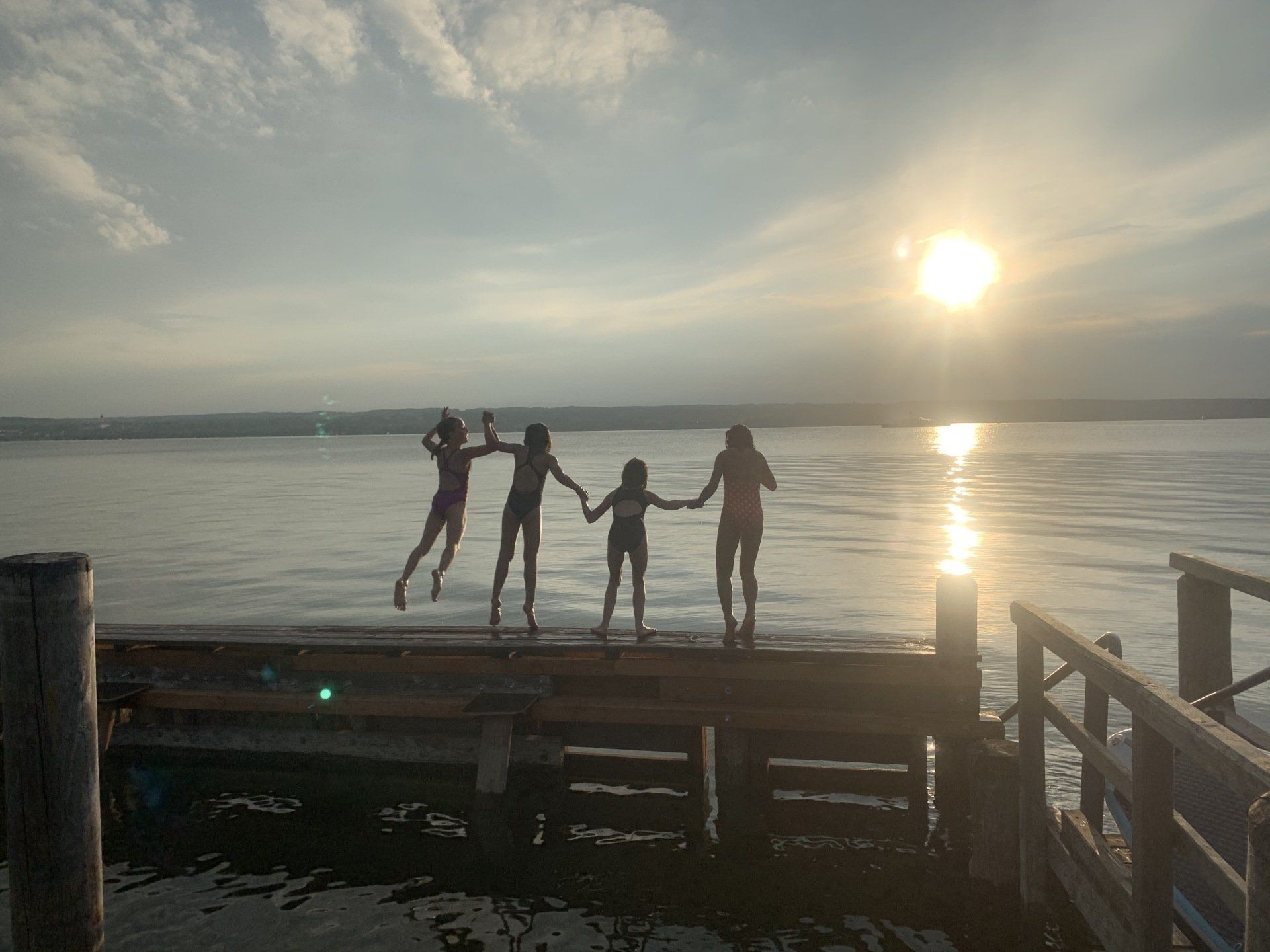 Eine Gruppe von Menschen steht auf einem Dock und hält sich an den Händen.