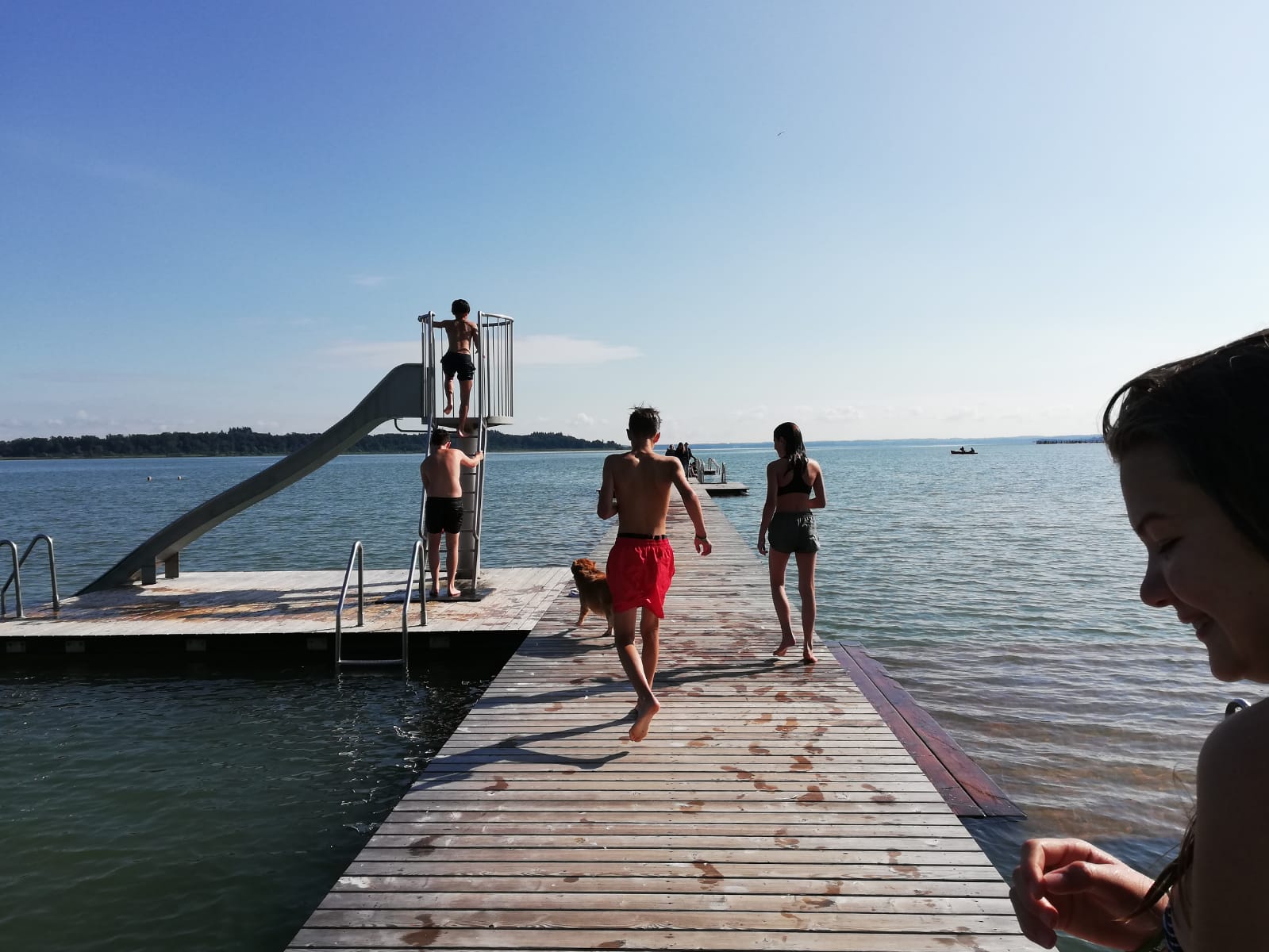 Eine Gruppe von Menschen steht auf einem Steg am Wasser.