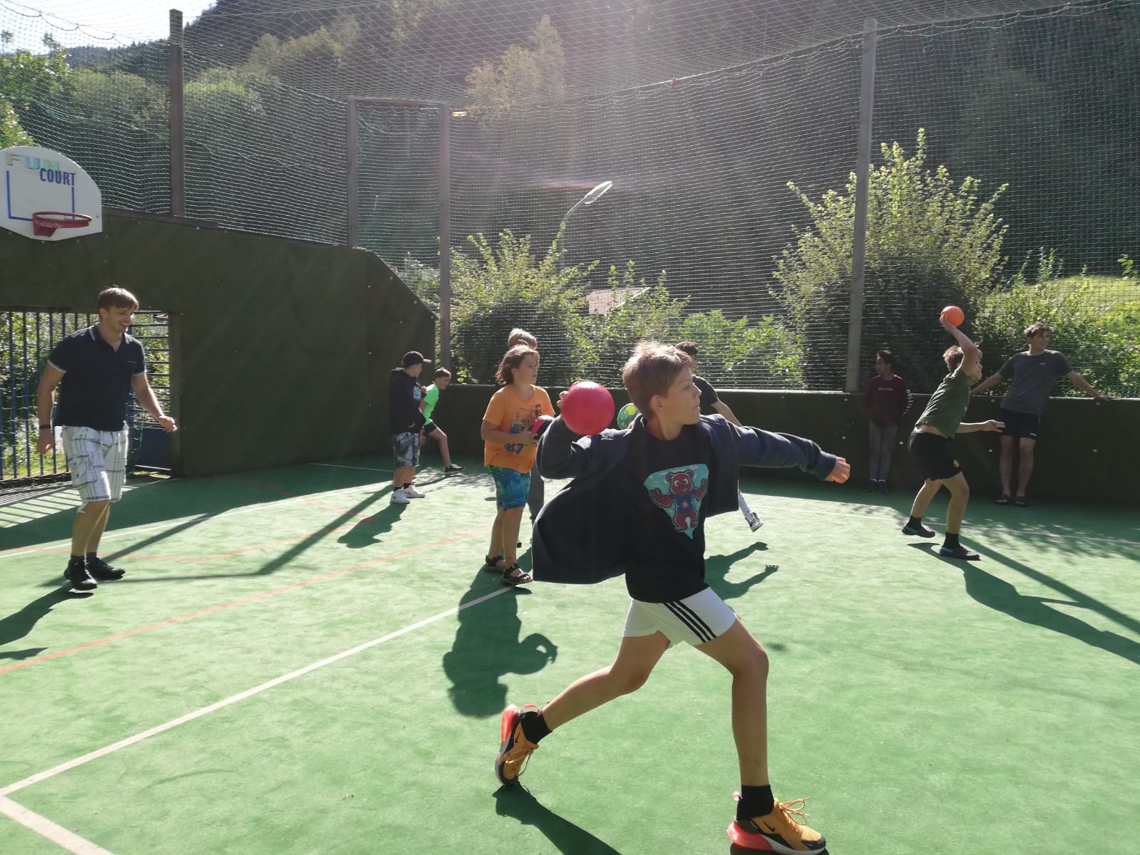 Eine Gruppe Kinder spielt Basketball auf einem Platz.