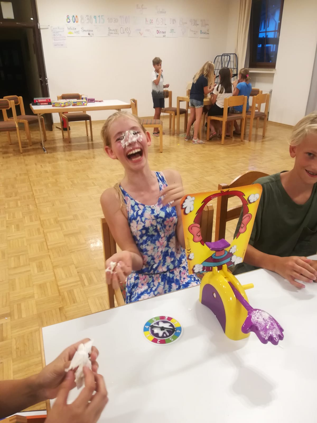Ein Mädchen sitzt an einem Tisch mit einem Spielzeug, auf dem die Nummer 16 steht