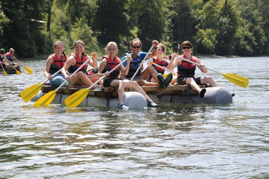 Eine Gruppe von Menschen rudert auf einem Floß im Wasser.