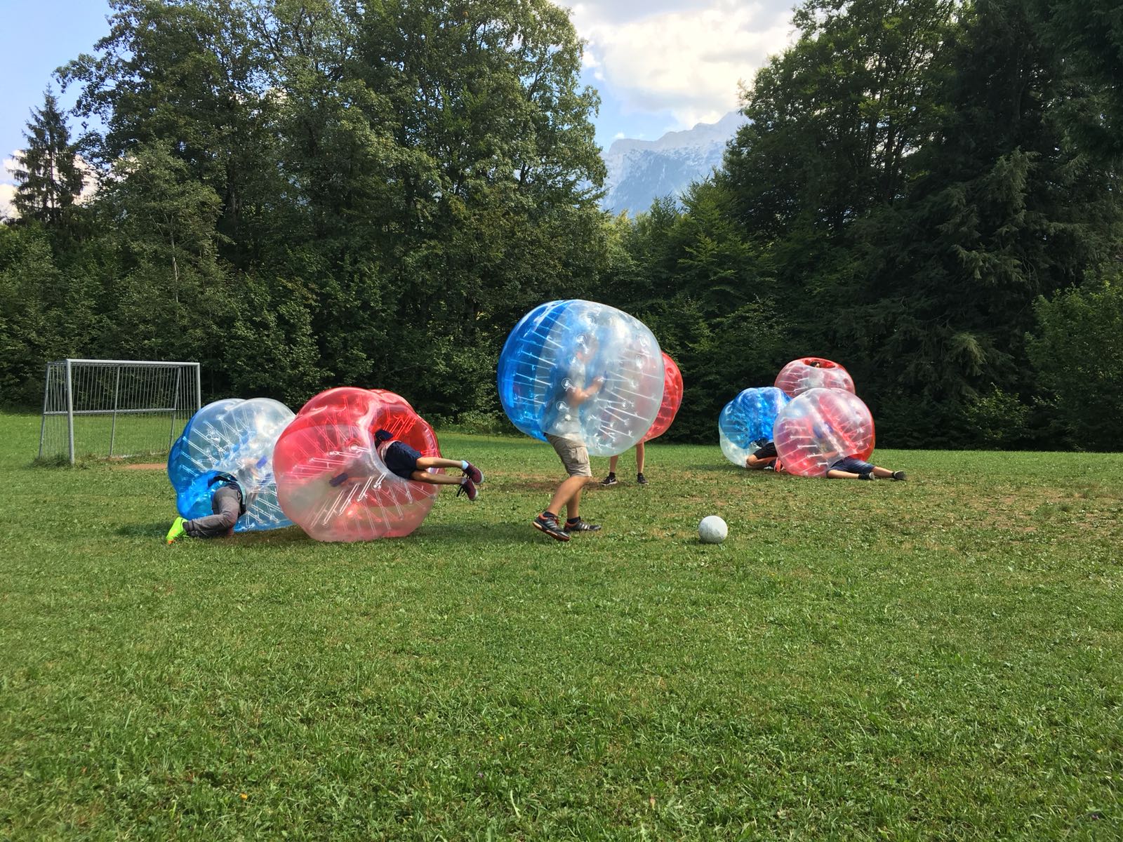 Eine Gruppe von Menschen spielt auf einem Feld Blasenfußball.