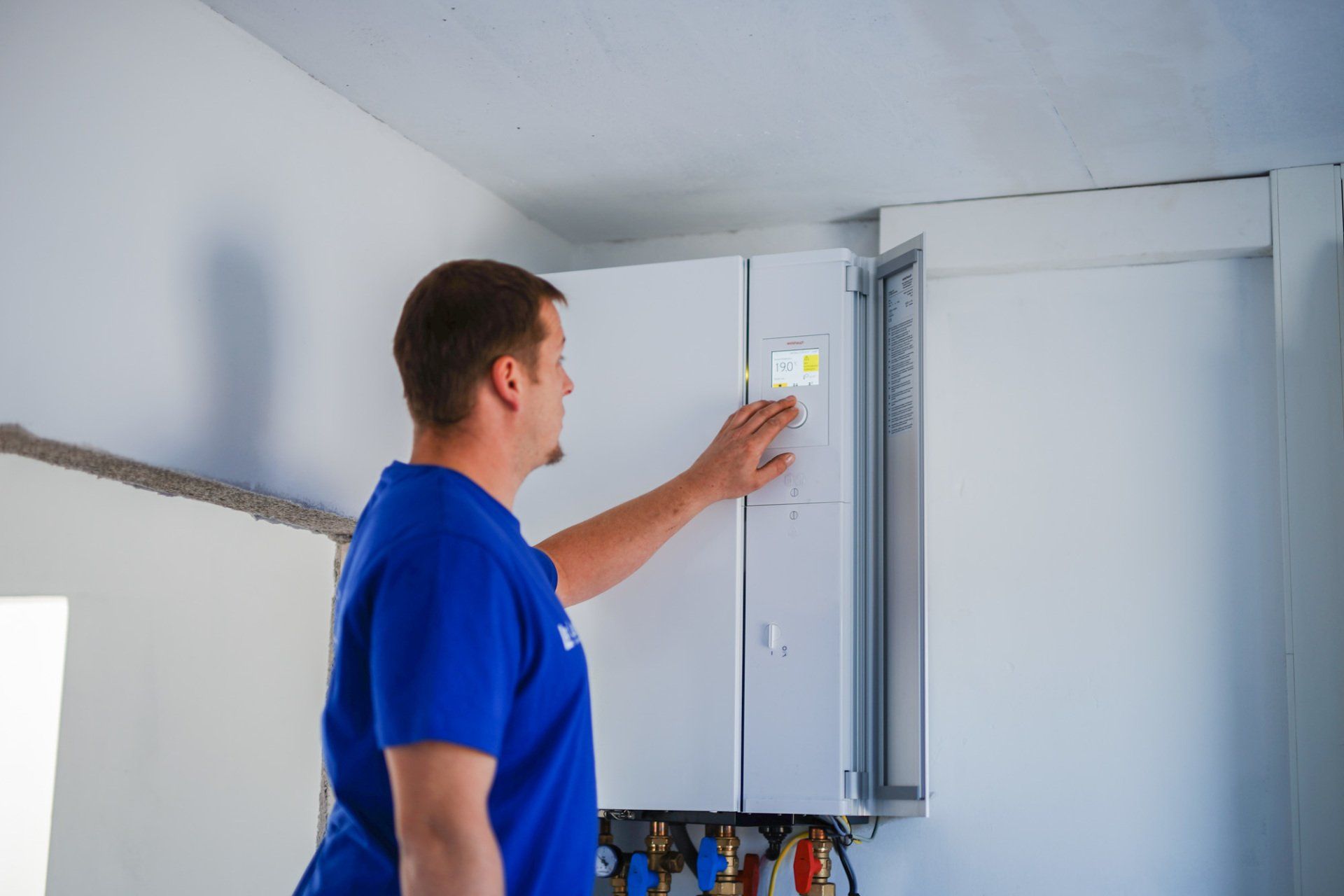 Ein Mann in einem blauen Hemd arbeitet in einer Küche an einem Boiler.