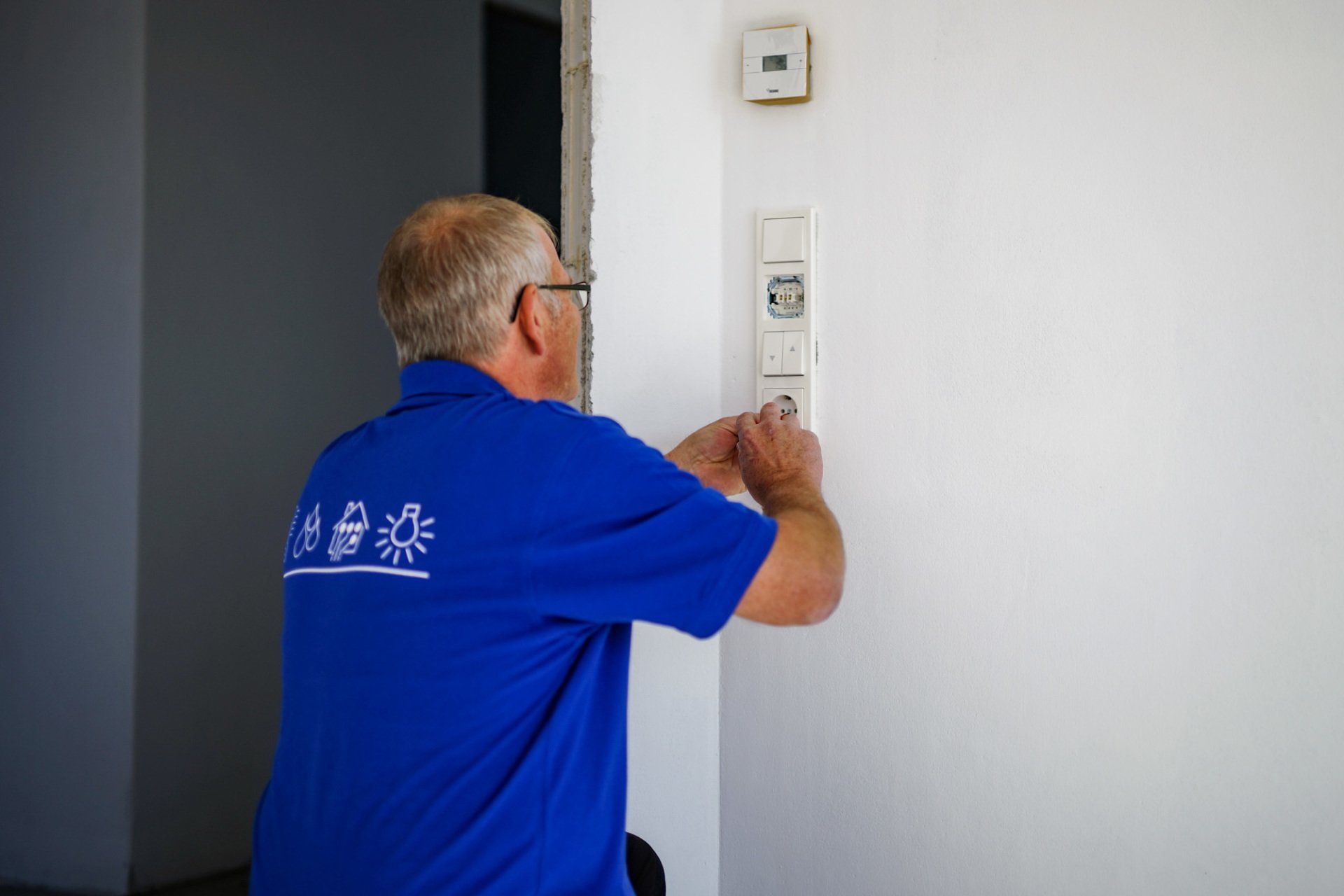 Ein Mann in einem blauen Hemd arbeitet an einem Lichtschalter.