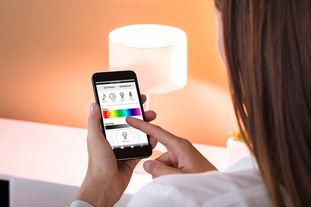 Eine Frau bedient eine Lampe über ein Smartphone.