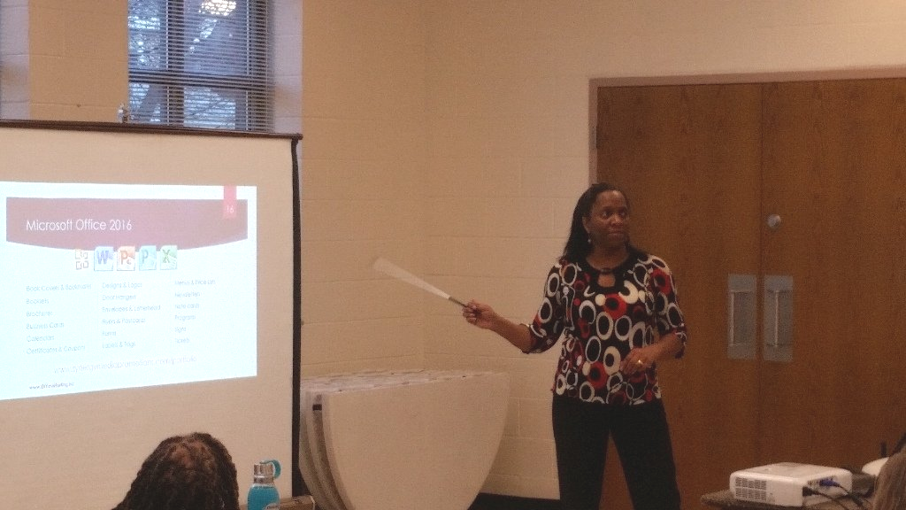 A woman is giving a presentation in front of a projector screen