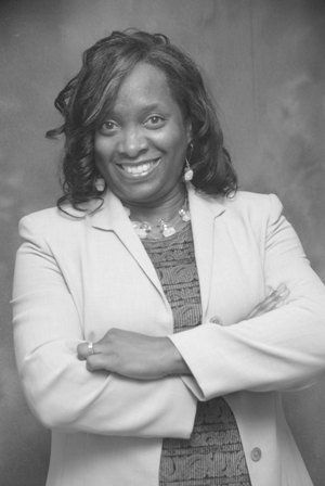 A black and white photo of a woman in a suit with her arms crossed.