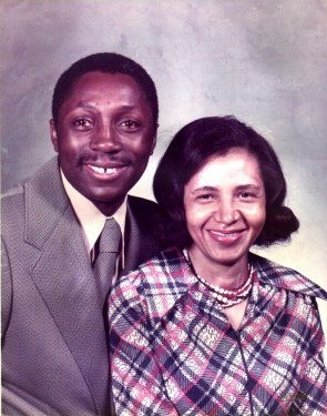 A man and a woman are posing for a picture and smiling for the camera.