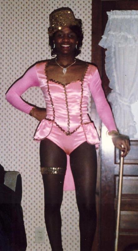A woman in a pink costume is holding a cane