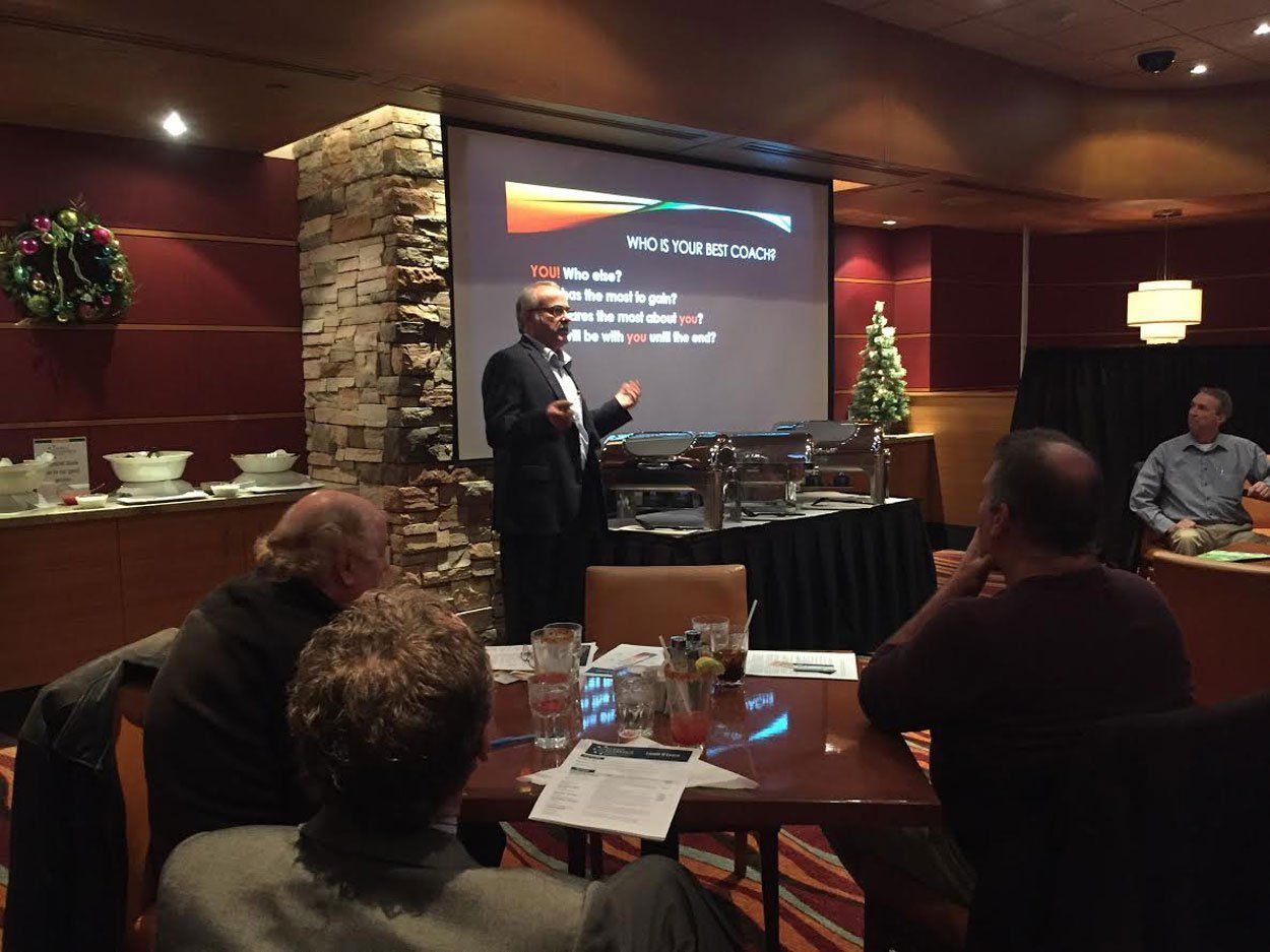 Man giving a presentation, using a projector, to a small audience in a restaurant.