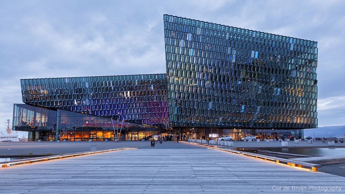 Harpa Concert Hall, Reykjavik, Iceland; glass facade reflecting colorful lights, near water.
