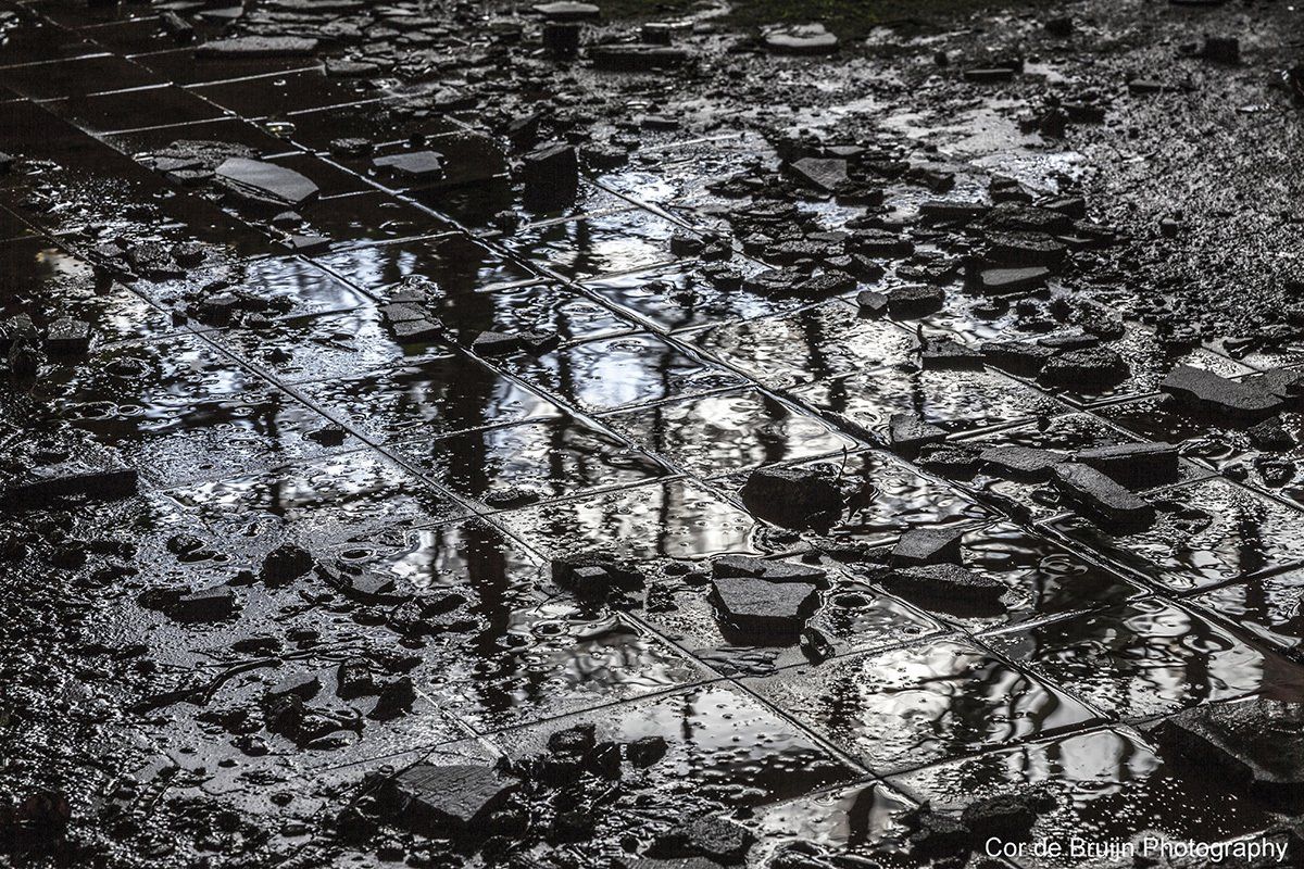 Overhead view of a reflective surface, possibly water, covering debris and architectural elements.