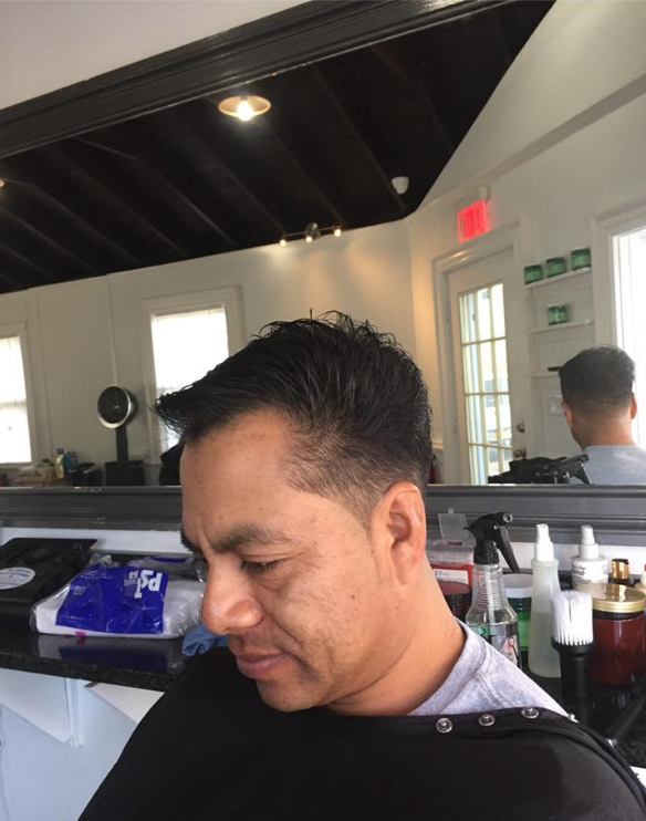 Man getting a haircut in a modern salon, with mirrors and product bottles visible behind him