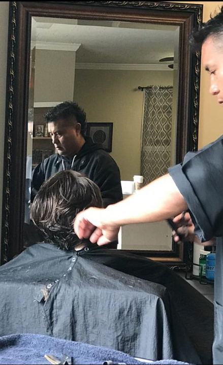 Hairdresser trimming a client's hair in front of a mirror in a salon.