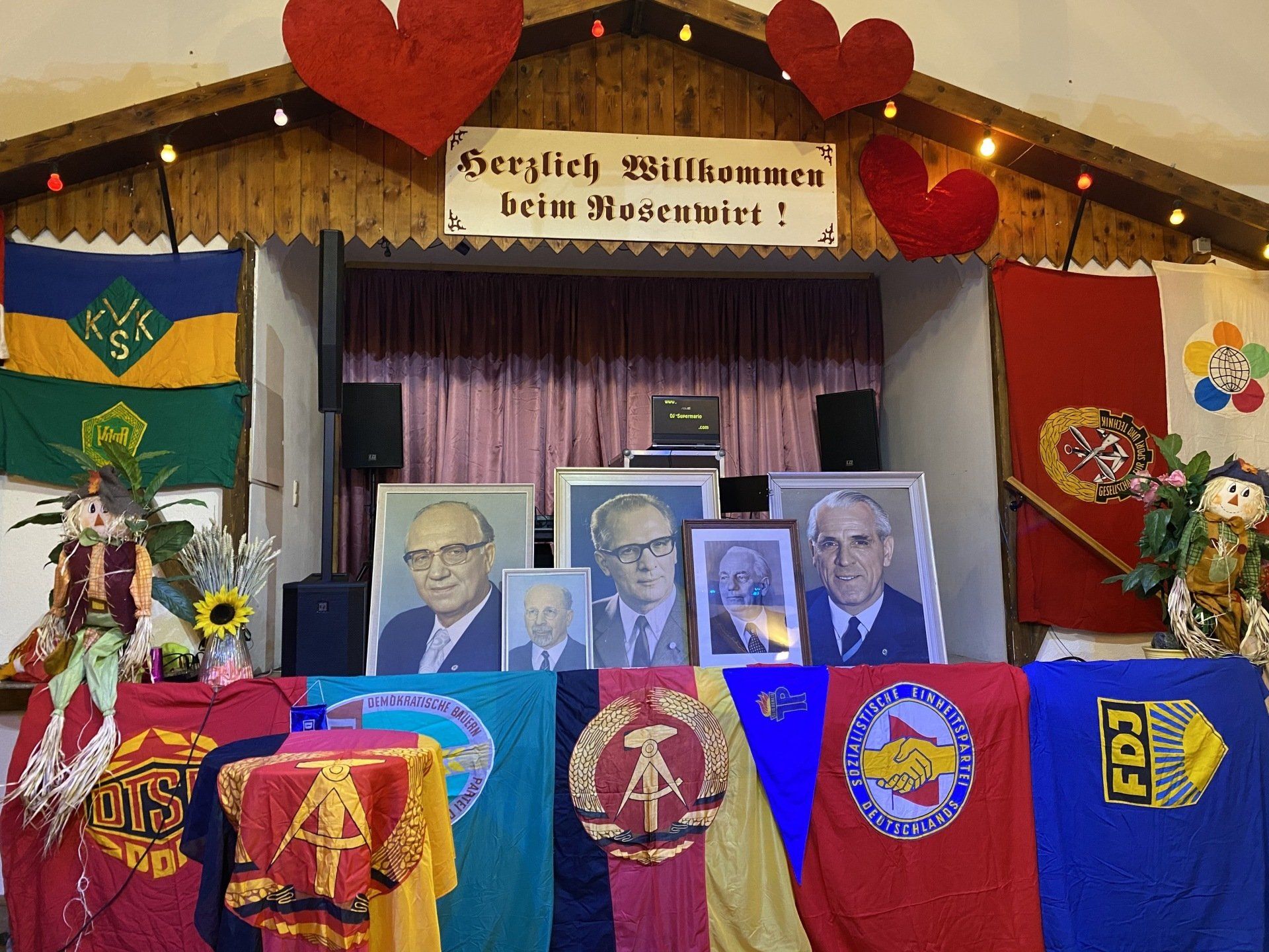 Stage decorated with flags, portraits, and a banner reading 