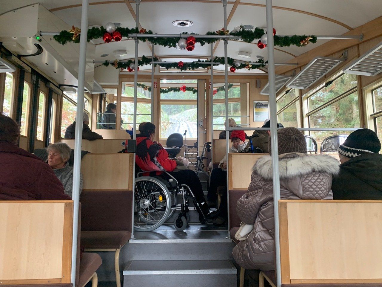 In einem dekorierten Straßenbahnwagen mit Passagieren ist eine Person im Rollstuhl zu sehen.