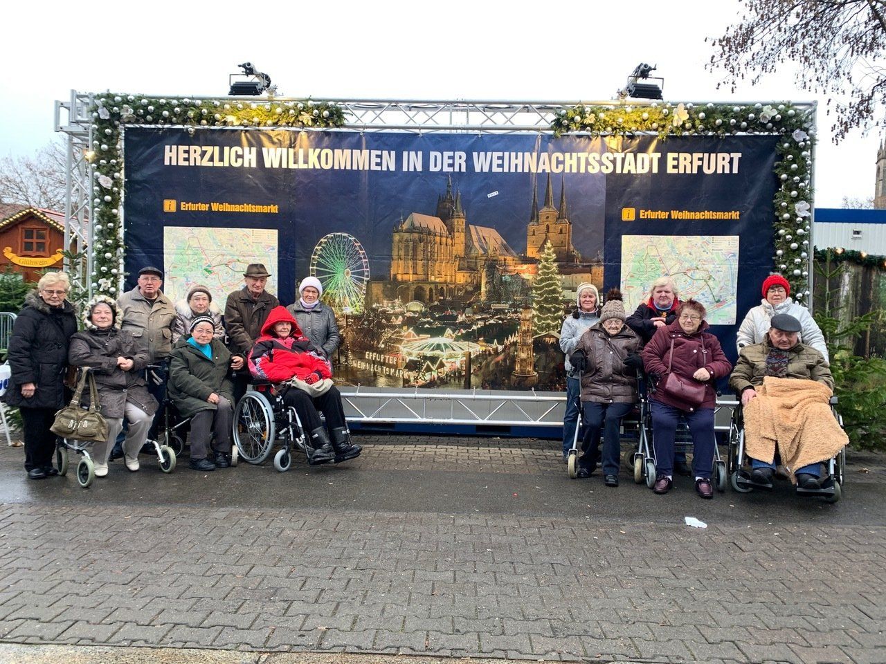 Eine Gruppe von Menschen, einige davon im Rollstuhl, posiert vor einem Banner in Erfurt. 