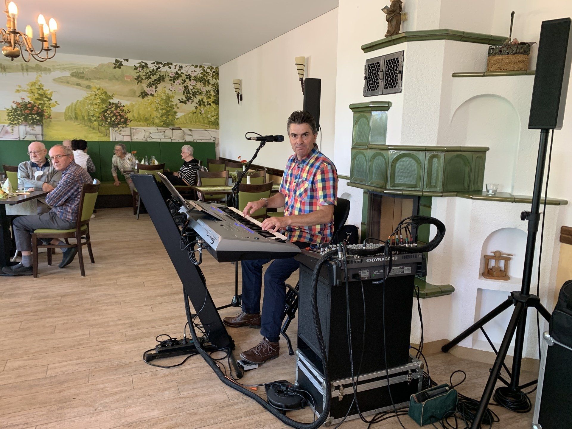 Mann spielt Keyboard und singt im Restaurant; Publikum sitzt.