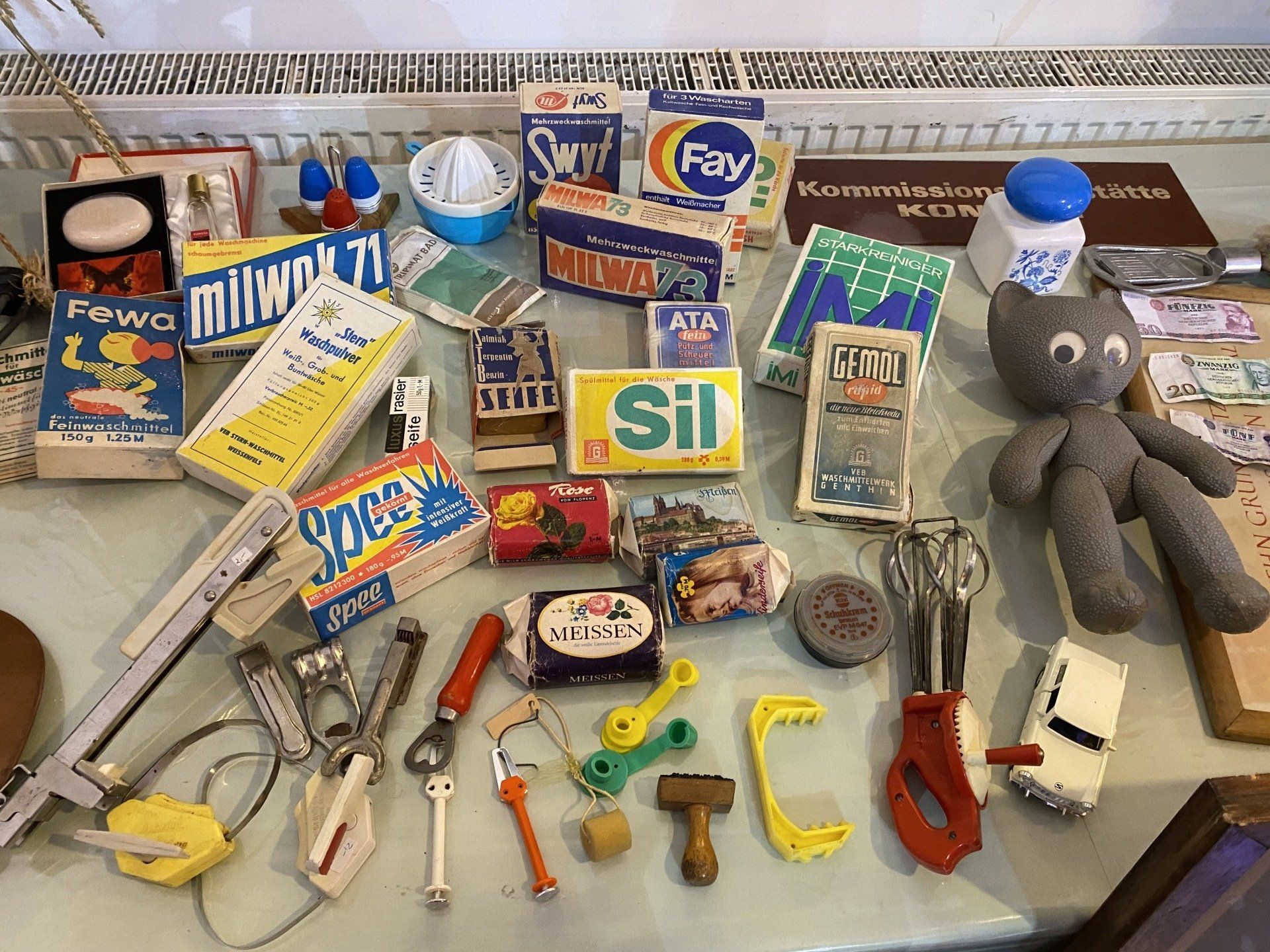 Sammlung von Vintage-Miniatur-Haushaltsgegenständen, darunter Seife, Schachteln, Küchengeräte und eine Katzenpuppe.