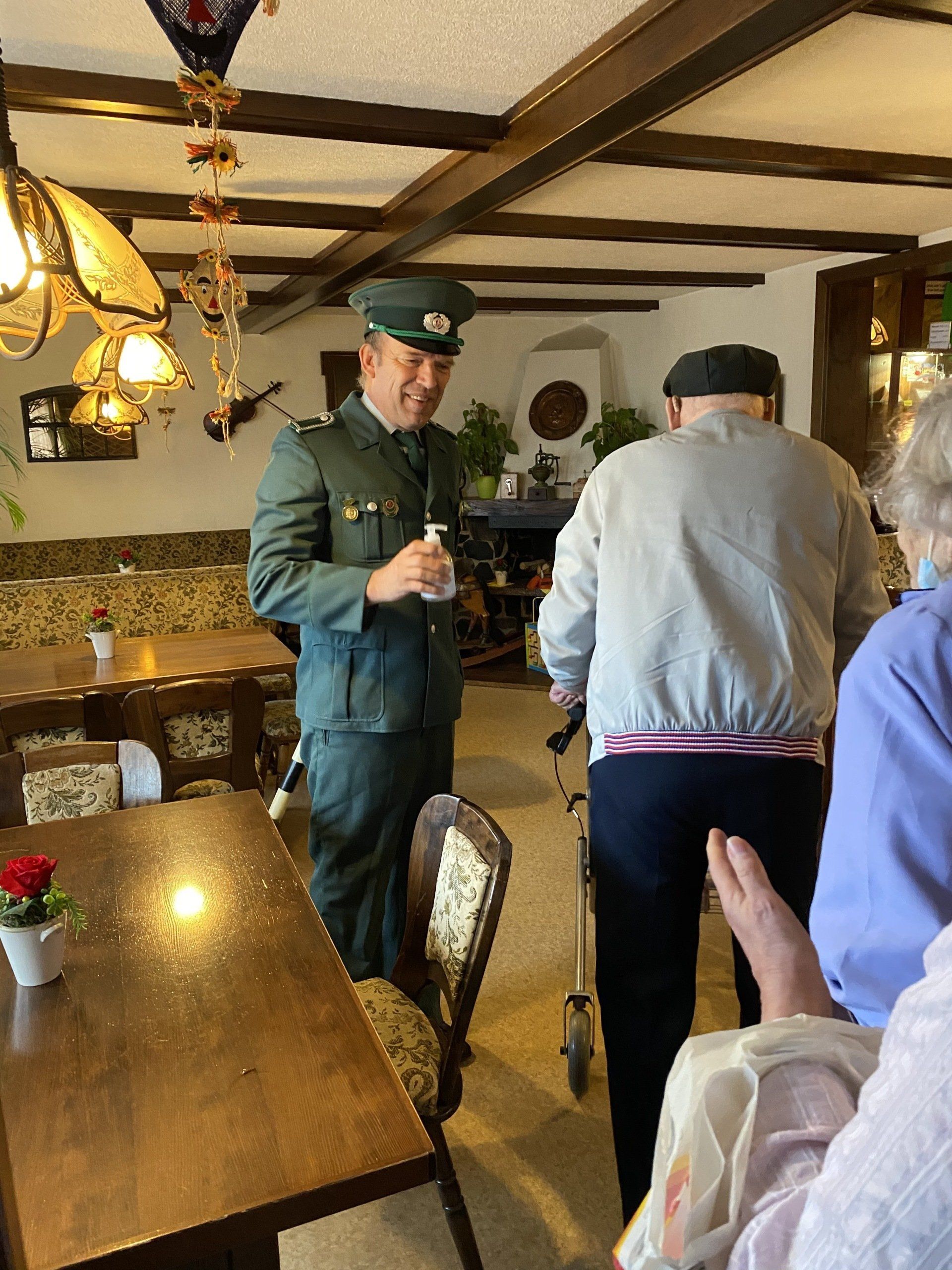 Mann in Uniform interagiert mit Leuten in einem Essbereich.