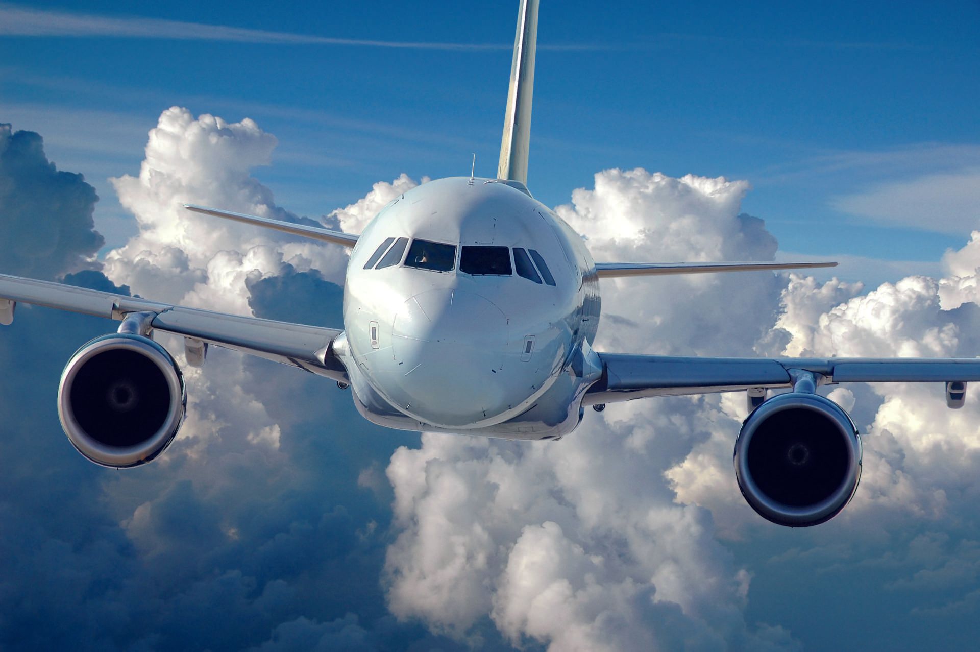 Ein Flugzeug fliegt durch einen blauen Himmel mit weißen, flauschigen Wolken.