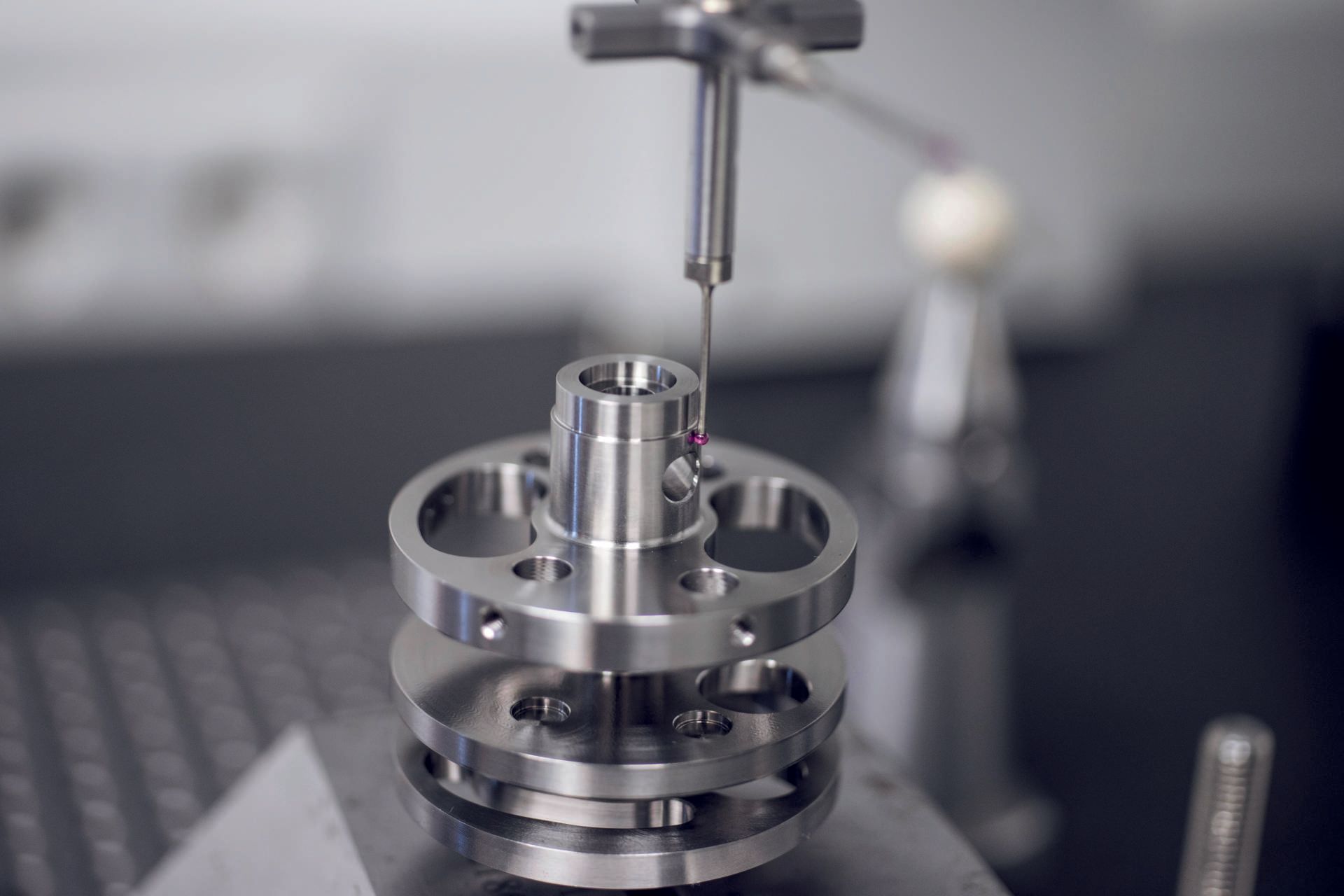 Nahaufnahme eines Metallteils, das in einer Fertigungsumgebung mit einem Präzisionsinstrument vermessen wird.