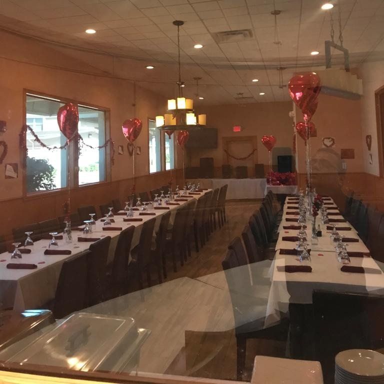 A long dining room with tables and chairs and balloons hanging from the ceiling