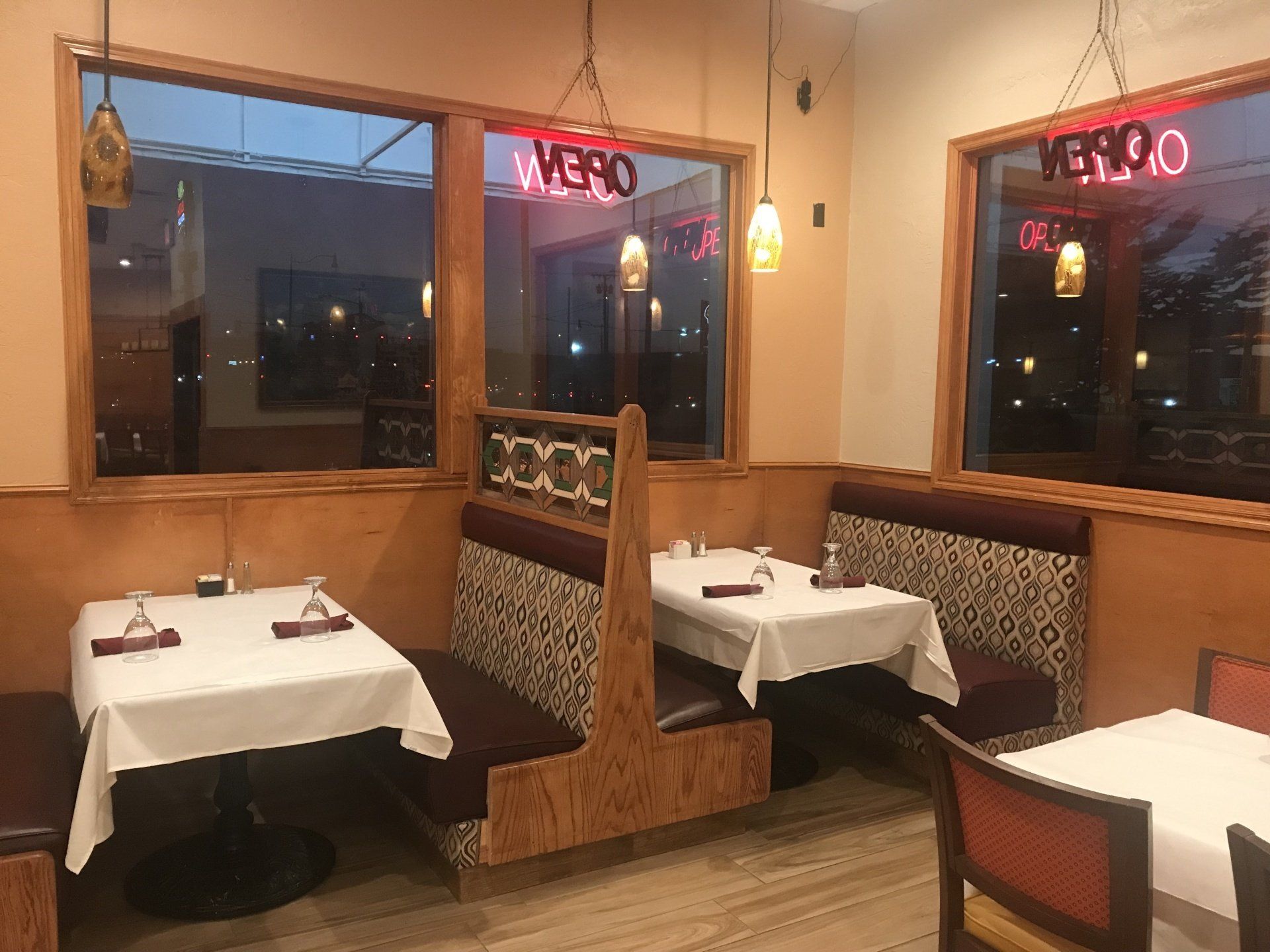A restaurant with tables and booths and a sign that says open.