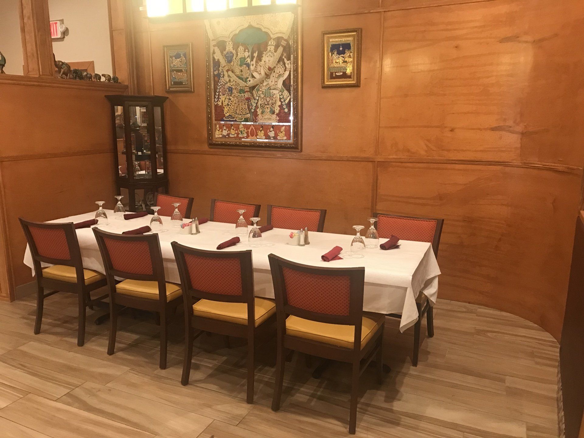 A long table and chairs in a restaurant with a wooden wall.