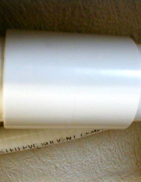 White roll of paper or plastic on a textured brown surface.