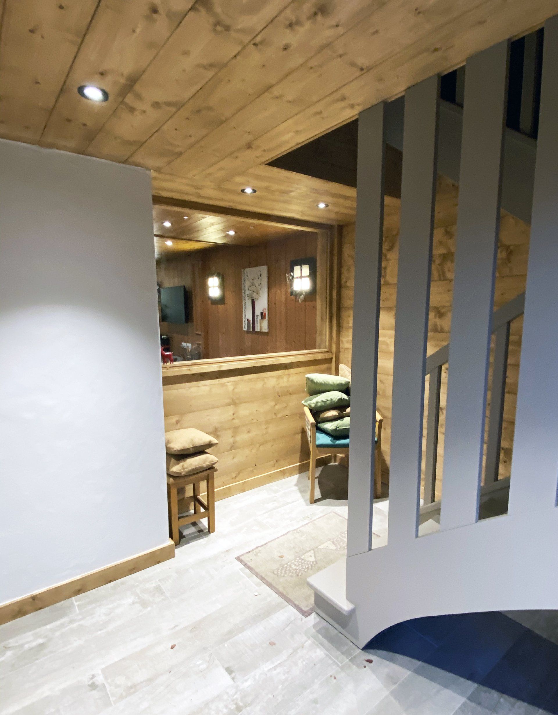 Intérieur lambrissé avec escalier en colimaçon, porte donnant sur un coin salon confortable et éclairage chaleureux