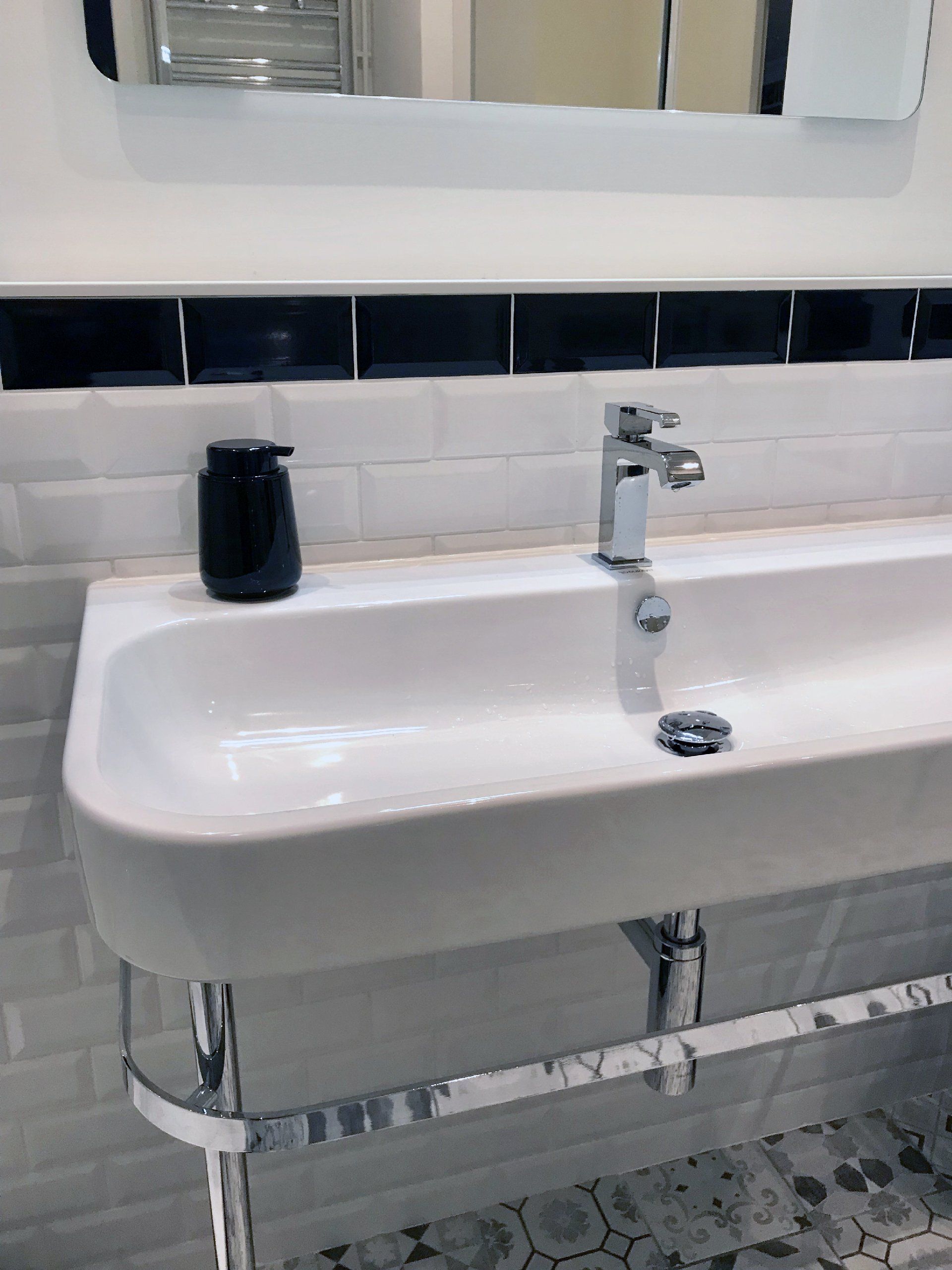 Lavabo de salle de bain blanc avec robinet chromé, miroir, accent de carrelage noir et carrelage au sol à motifs