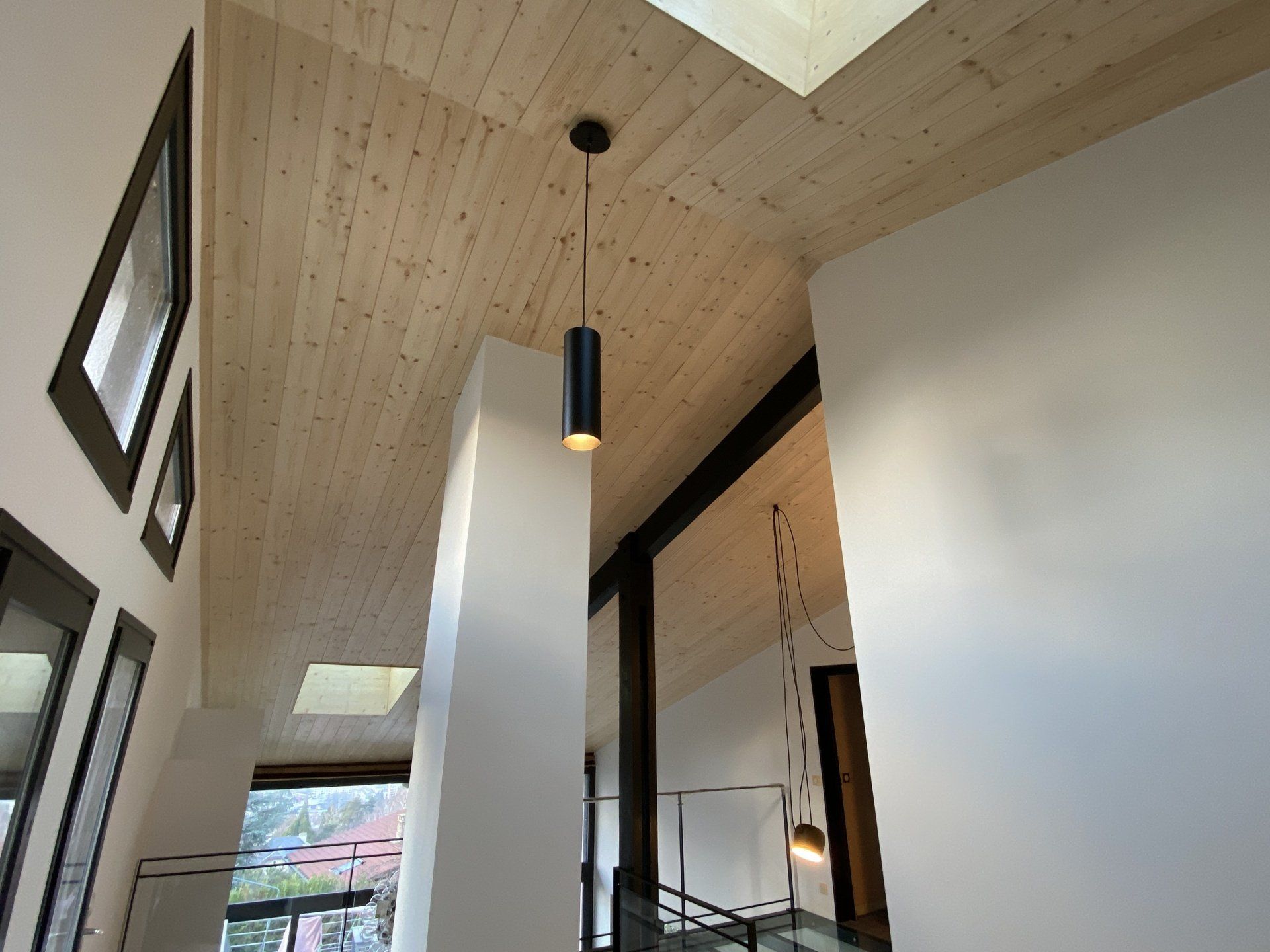 Intérieur moderne avec hauts plafonds, puits de lumière, murs blancs et une suspension lumineuse 