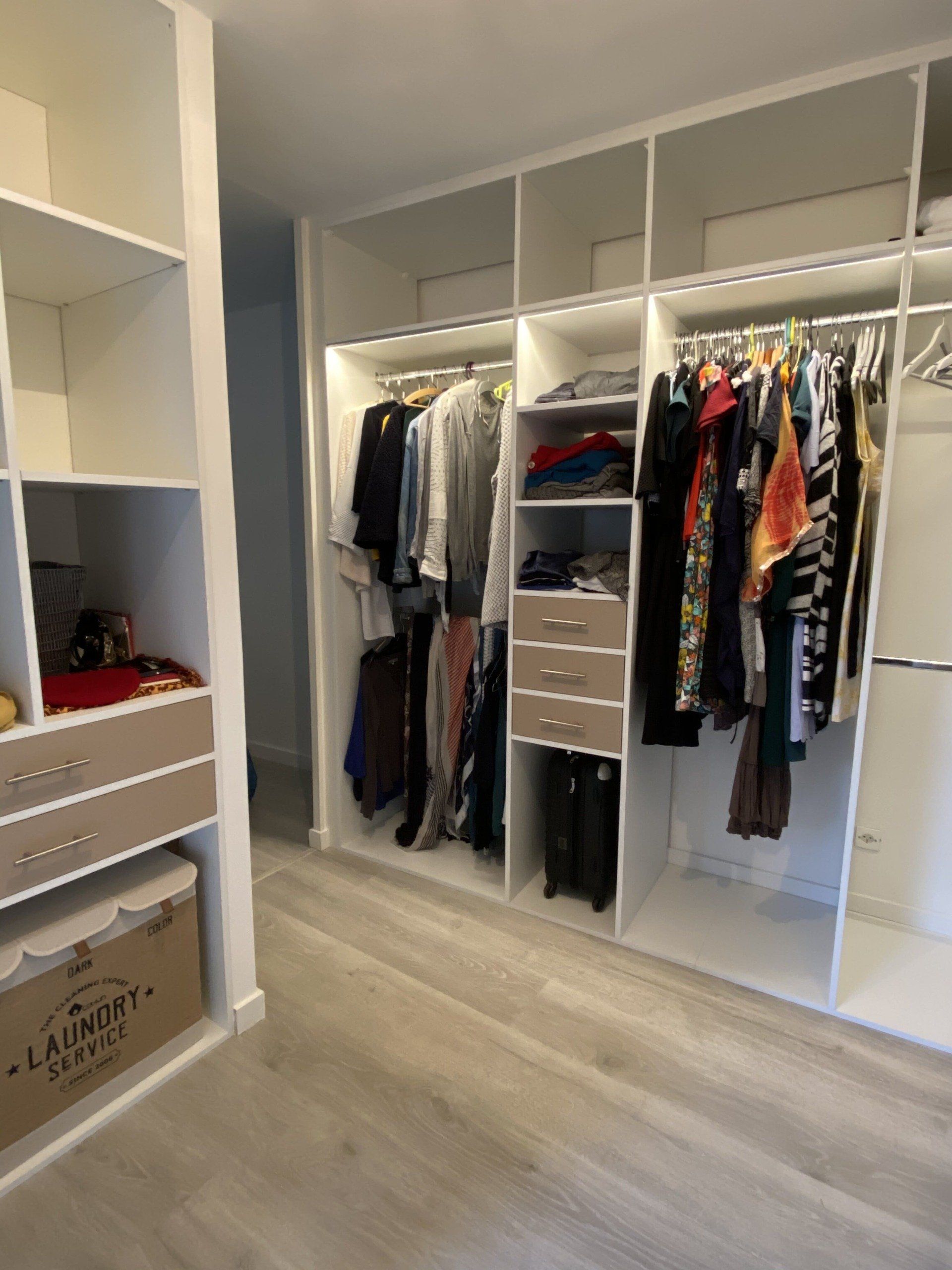 Dressing avec étagères blanches, penderie, tiroirs et parquet clair