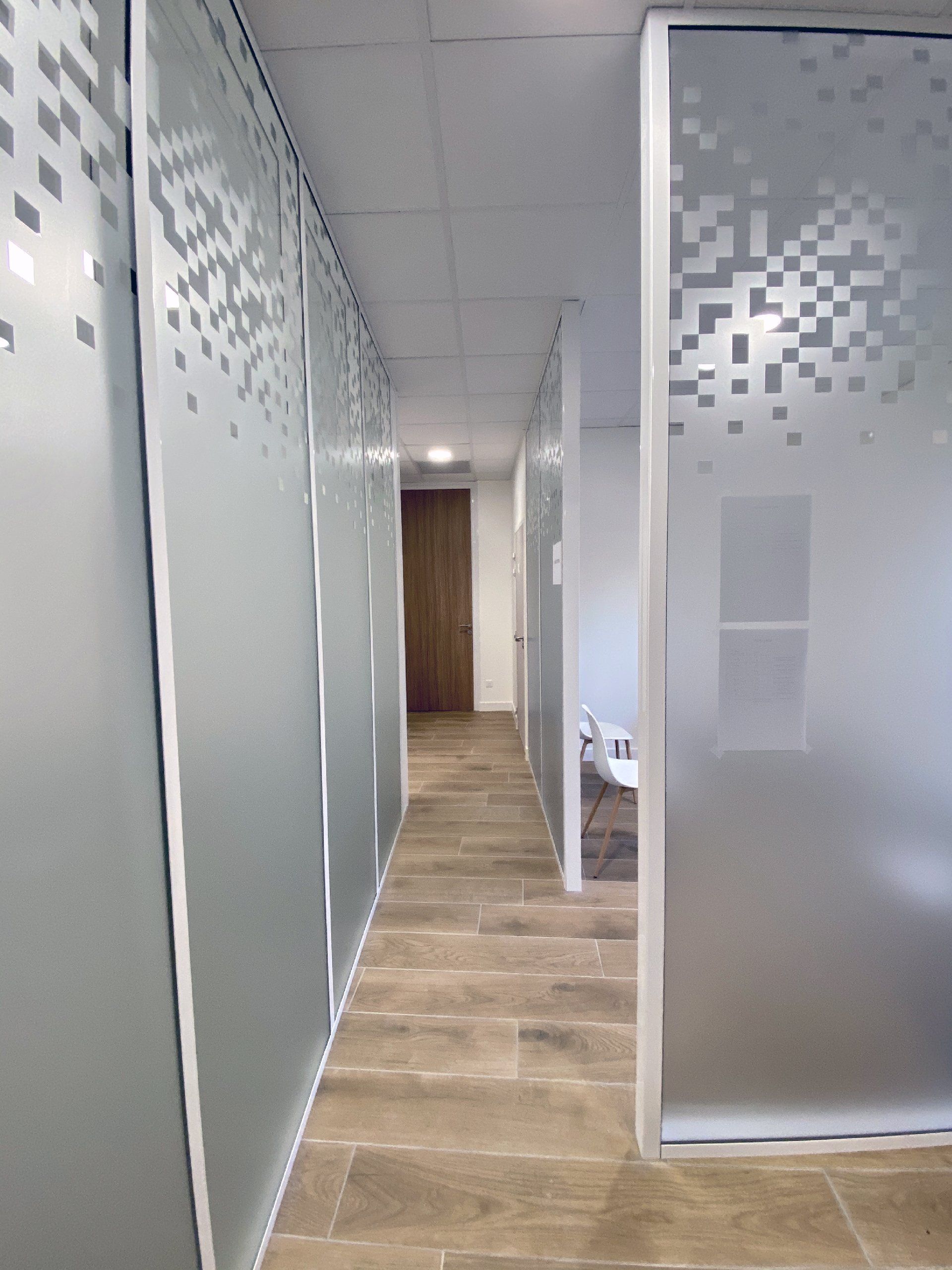 Couloir de bureau moderne avec cloisons en verre, panneaux dépolis et carrelage imitation bois