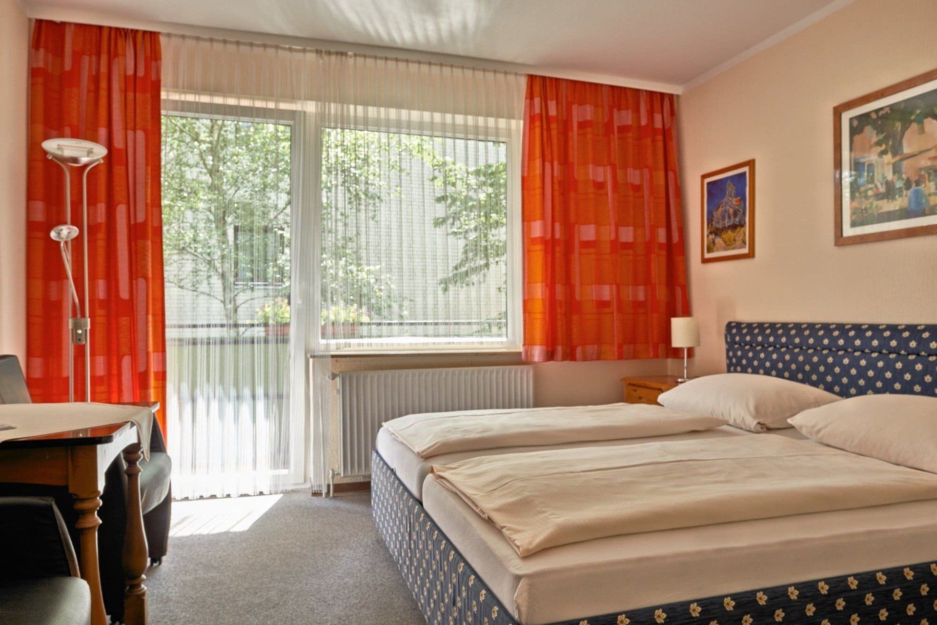 Ein Hotelzimmer mit zwei Betten, einem Tisch und einem Stuhl.