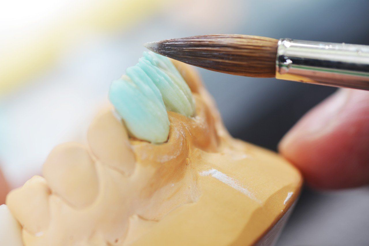 A person is painting a tooth with a brush.
