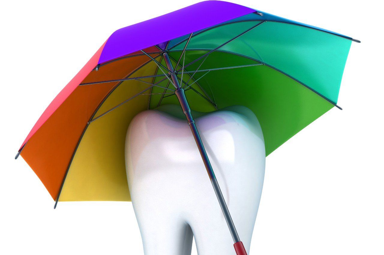 A tooth with a rainbow colored umbrella over it.
