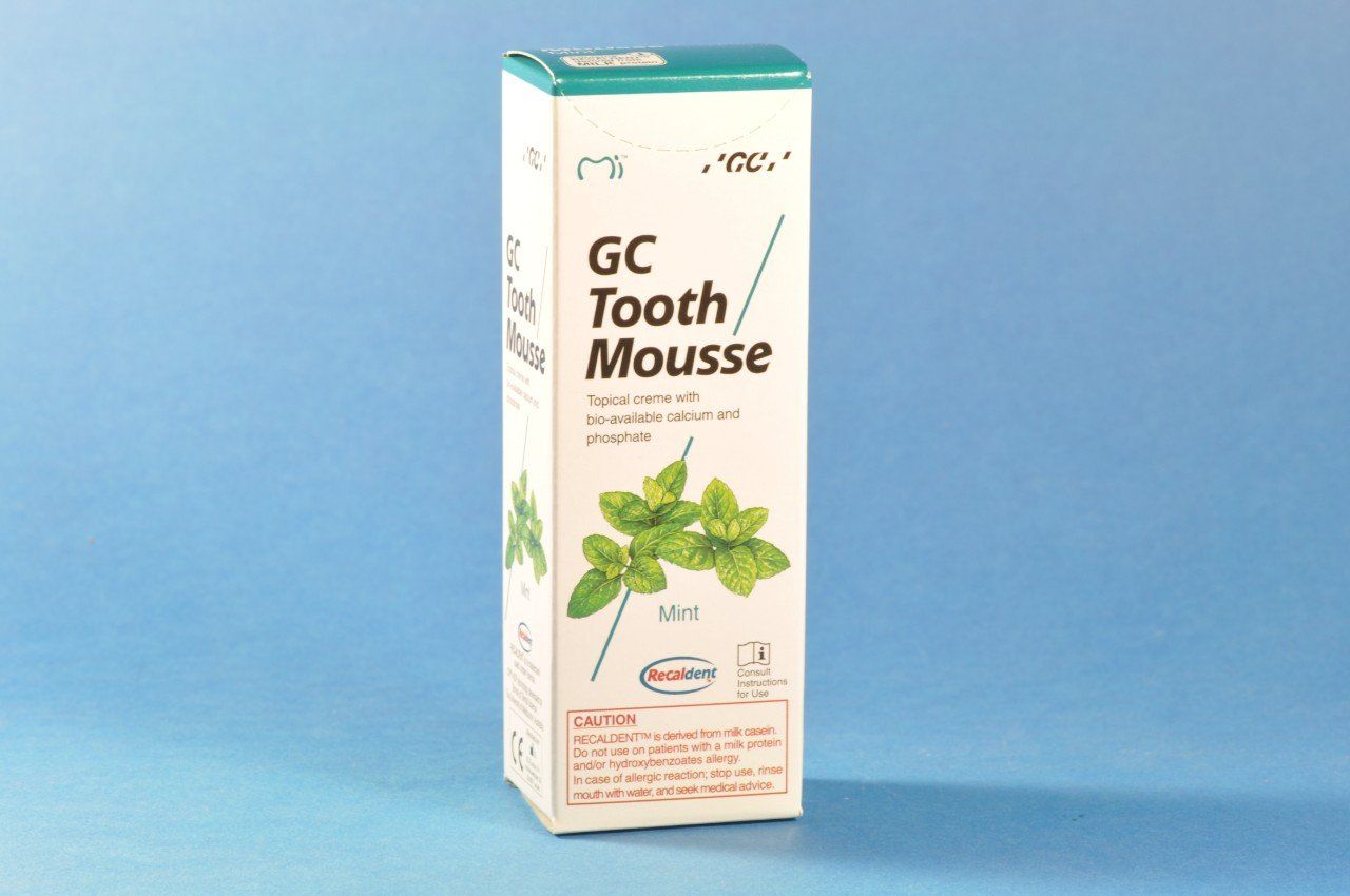 A box of gc tooth mousse on a blue surface