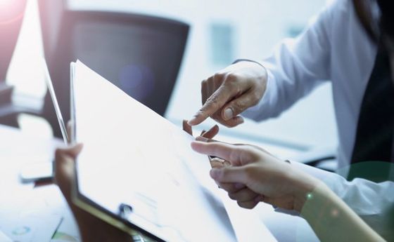two people pointing at a paper on clipboard