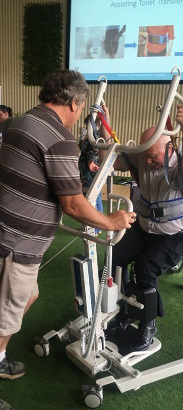 Two people adjusting a white robotic assistive device in a classroom or demo setting. — Health Experts In Toowoomba, QLD