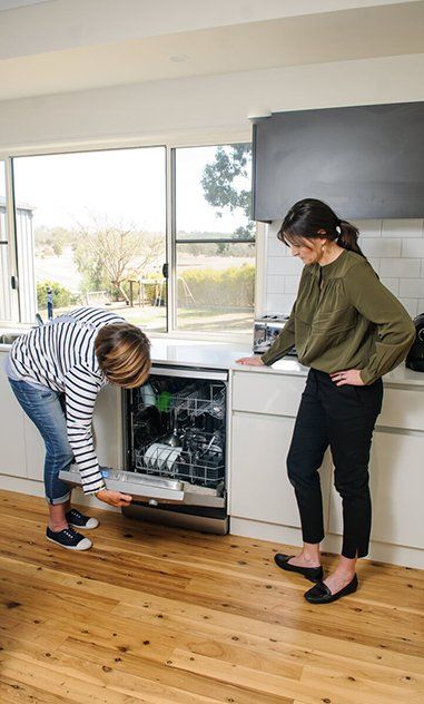 Two people inspecting an open dishwasher in a bright kitchen with a large window — Health Experts In Toowoomba, QLD