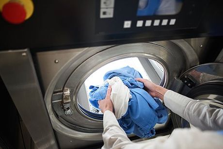 Mani mettono i vestiti in lavatrice LECOLAVANDERIA srl Caramagna Piemonte
